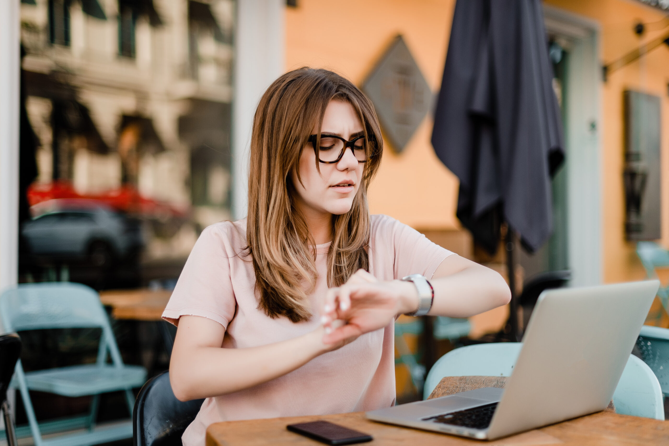 young concerned woman checking time using laptop freelance work cafe scaled