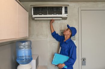 Young Asian technician checking conditioner in kitchen