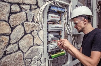 male-electrician-works-switchboard-with-electrical-connecting-cab-min